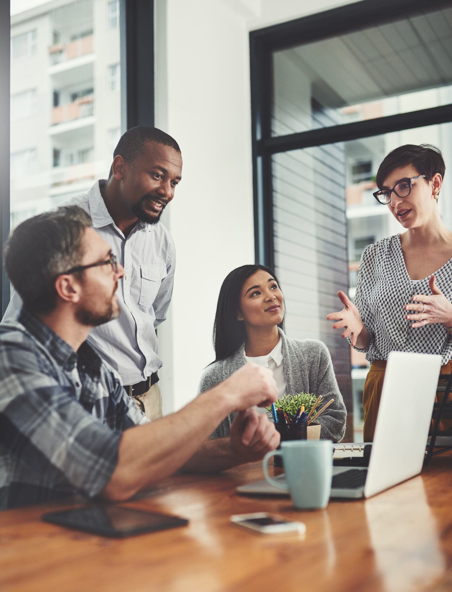 Four people engaged in enthusiastic discussion around a laptop
